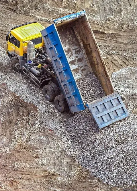 A Yellow Dump Truck With Its Blue Container Raised — Copp & Co Civil Plant Hire in Mount Julian, QLD