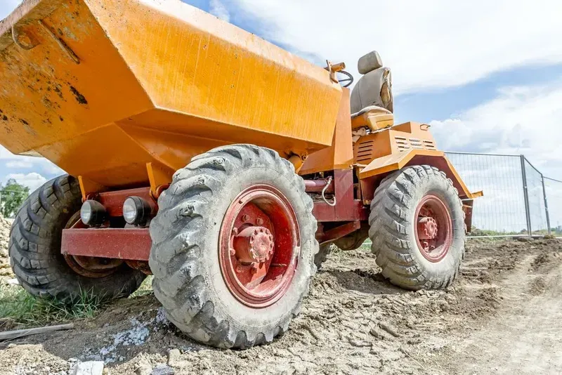 An Orange, Industrial Dumper Truck Sits on a Dirt Construction Site — Copp & Co Civil Plant Hire in Airlie Beach, QLD