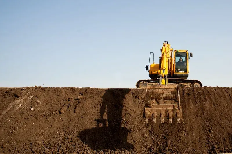 A Yellow Excavator Sits Atop a Large Mound of Dark Soil — Copp & Co Civil Plant Hire in Proserpine, QLD