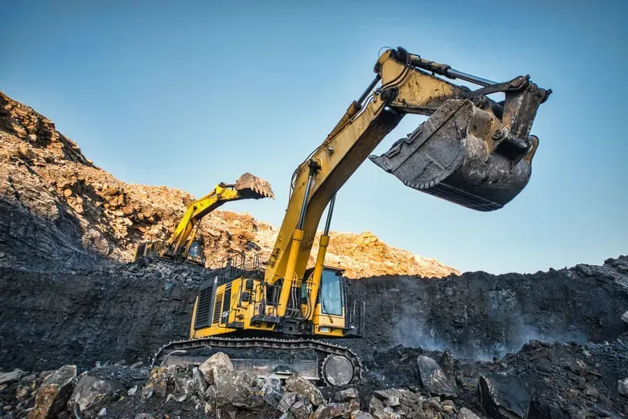 Two Yellow Excavators Work in a Rocky, Open-pit Mine Under a Clear Blue Sky — Copp & Co Civil Plant Hire in Mount Julian, QLD