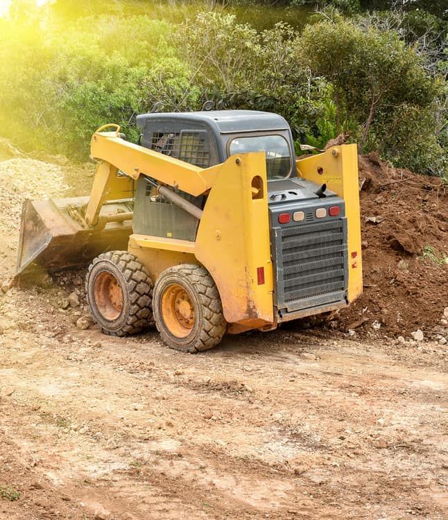 A Yellow Skid-steer Loader Parked on a Dirt Path With a Pile of Earth — Copp & Co Civil Plant Hire in Mount Julian, QLD