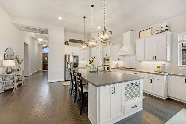 Bright white modern kitchen with island, pendant lights, and dark wood floors