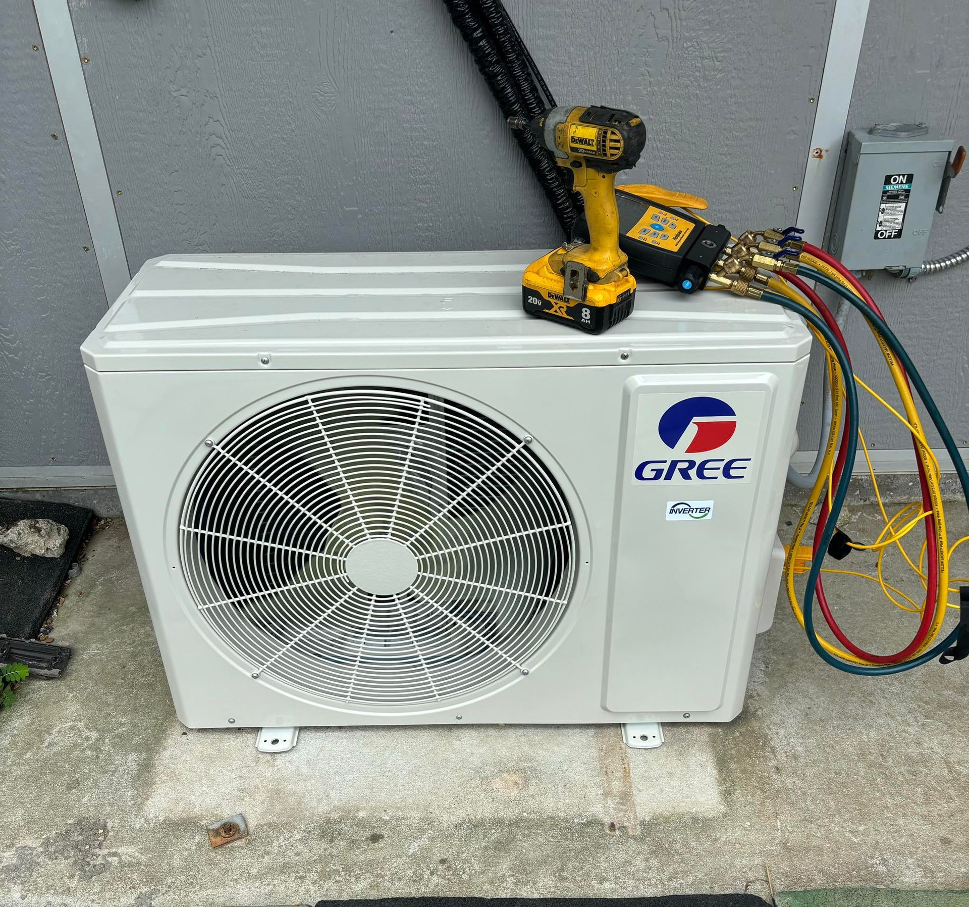 A Gree air conditioning unit outside with tools connected for maintenance.