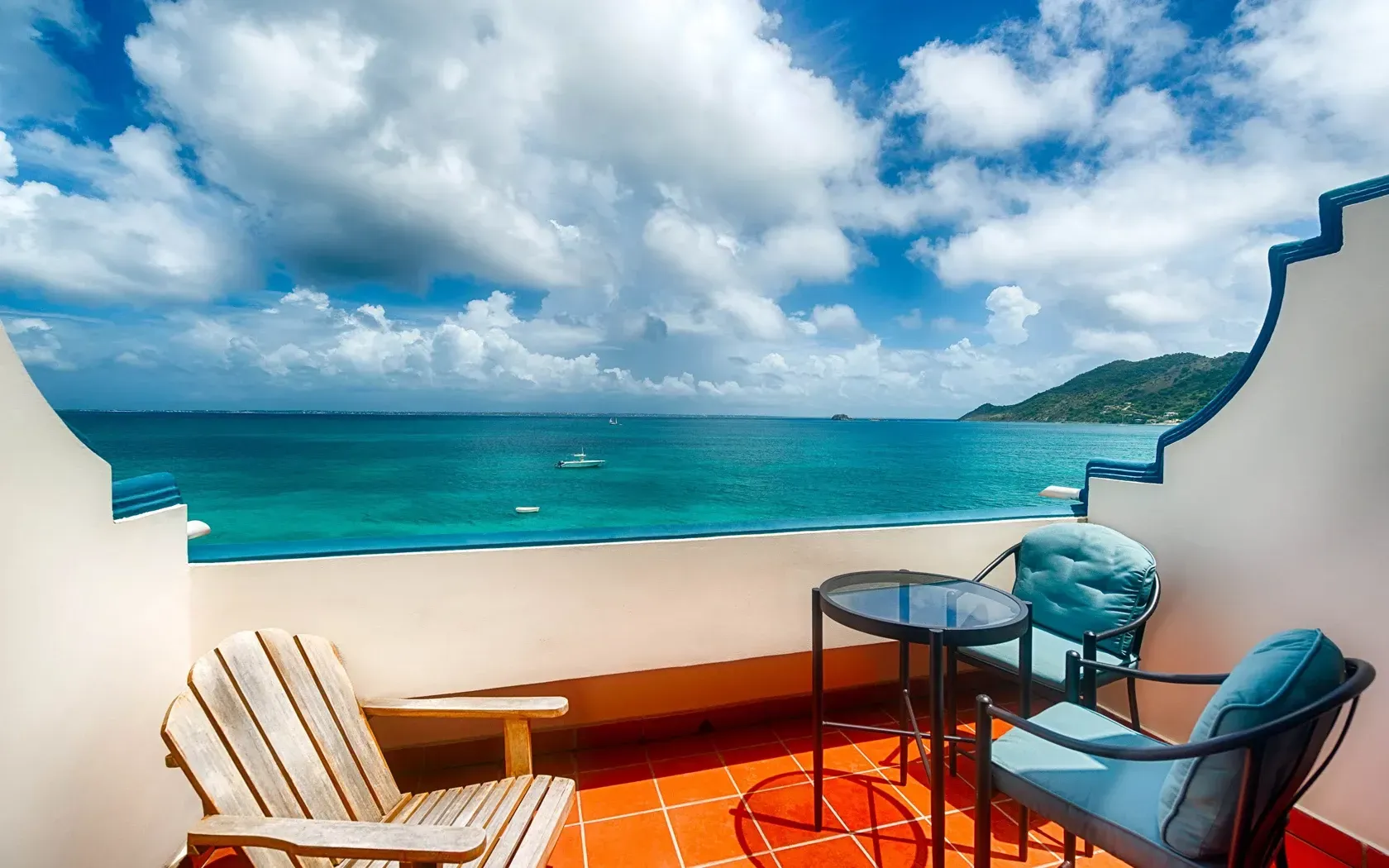 Balcony with ocean view: Two chairs, small table. Blue water, sky, and wood chair.