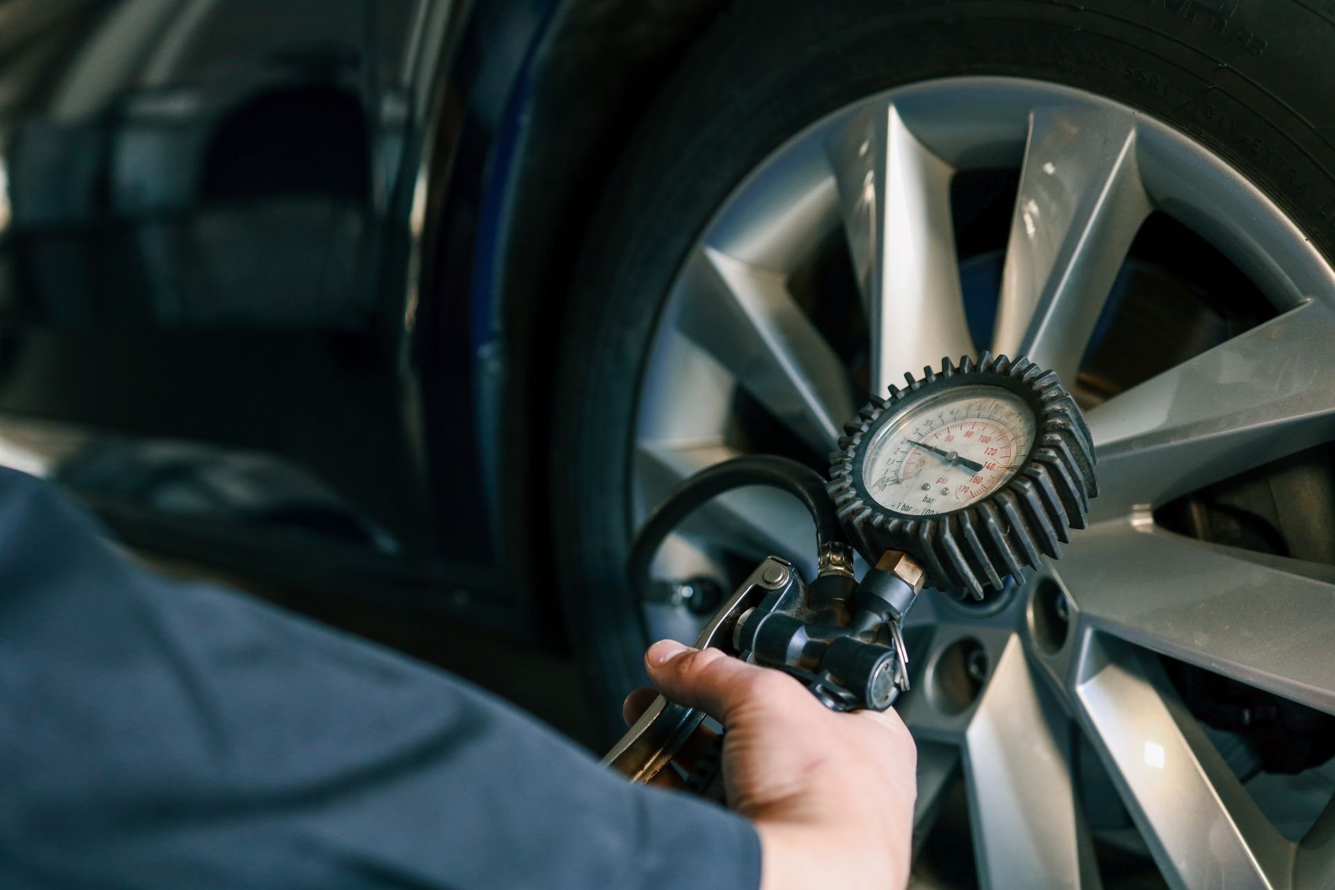Mechanic using a tire pressure gauge on a car wheel