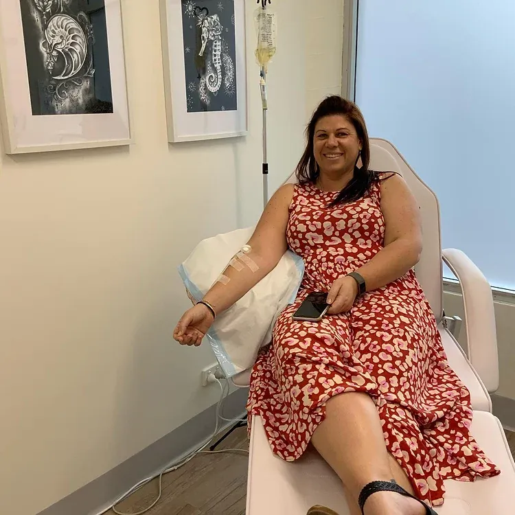 A woman in a red dress is sitting in a hospital bed