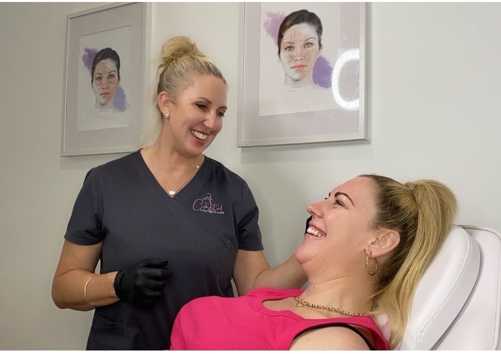 A woman is laughing while sitting in a chair next to a nurse.