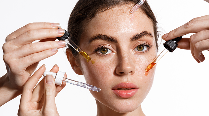 A woman is applying a serum to her face with a pipette.
