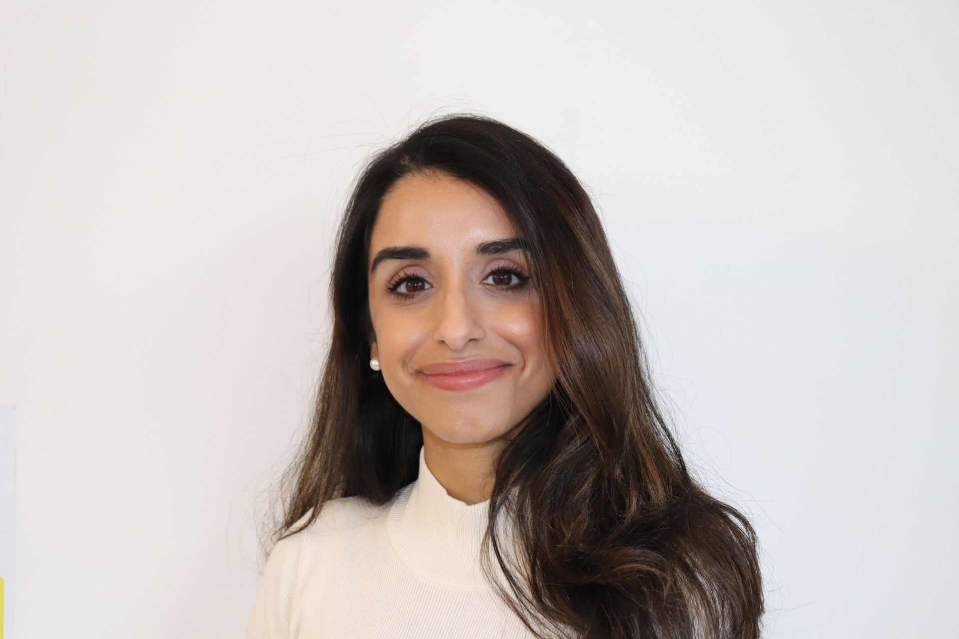 A woman with long hair is smiling for the camera while wearing a white shirt.