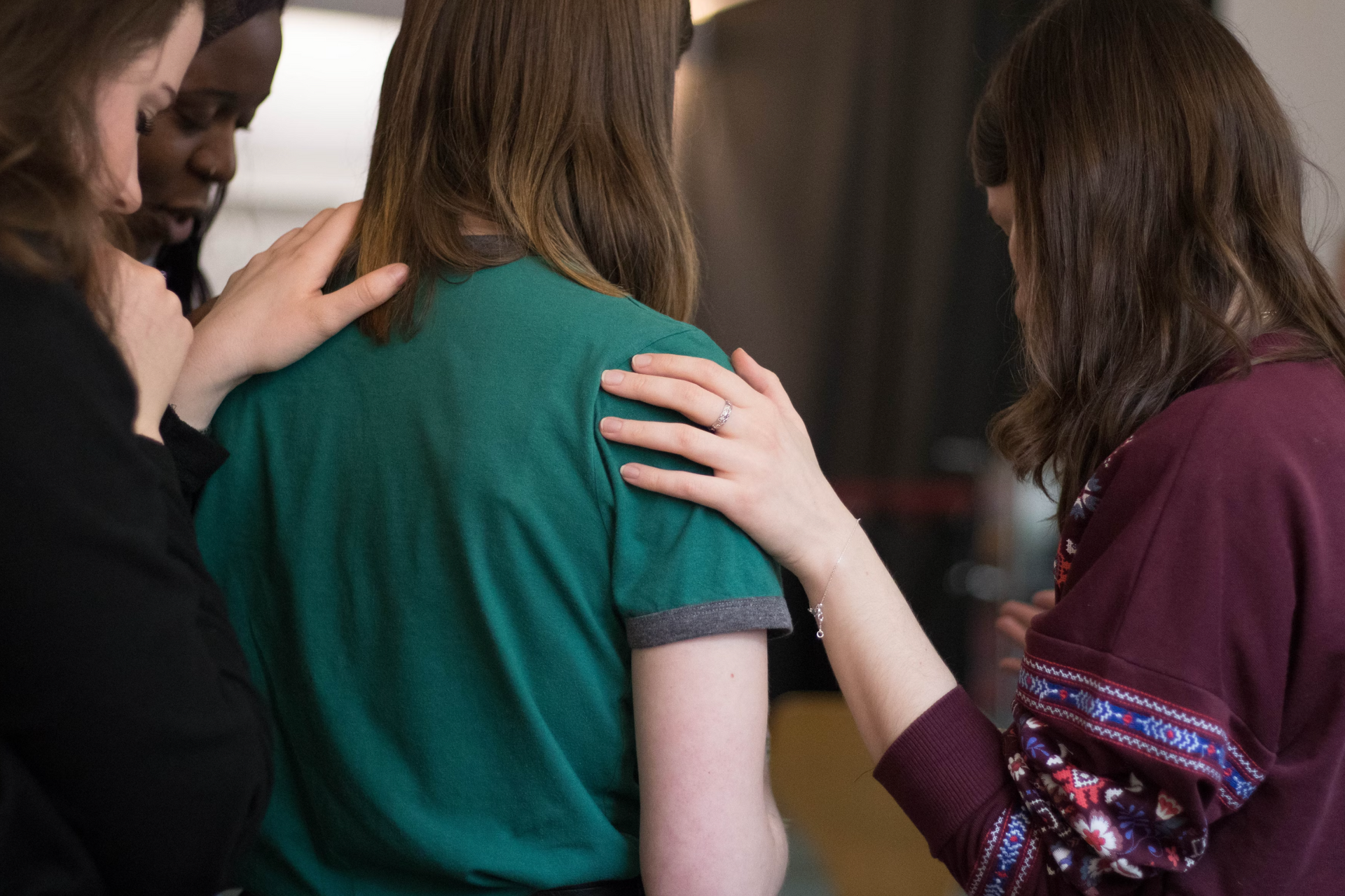 Three women are standing next to each other with their hands on each other 's shoulders.