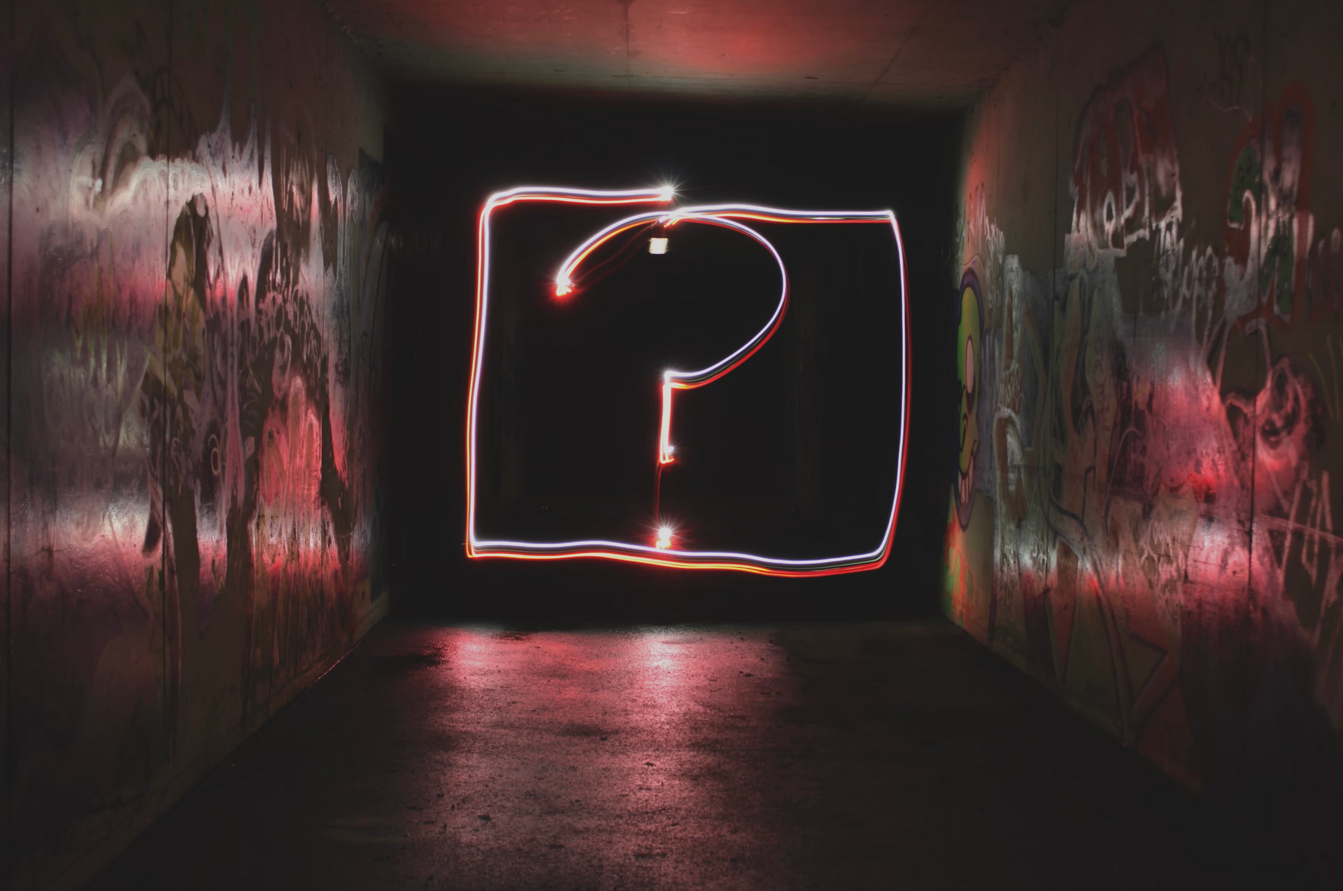 A light painting of a question mark in a dark tunnel.