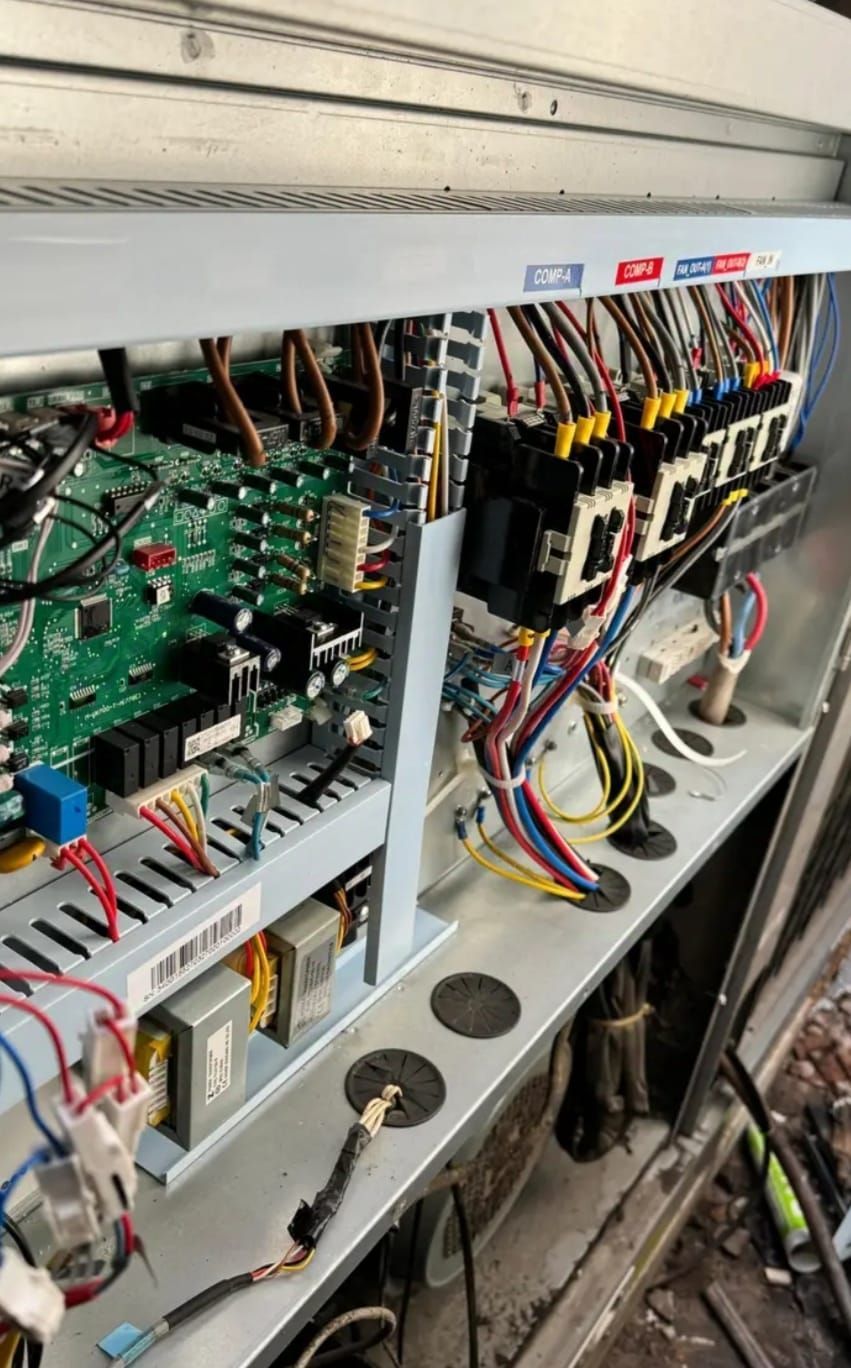 Panel de control eléctrico abierto con placas de circuitos, cables y contactores.