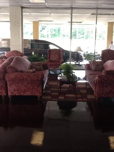 Hotel lobby seating area with red armchairs, glossy floor, and large windows in back