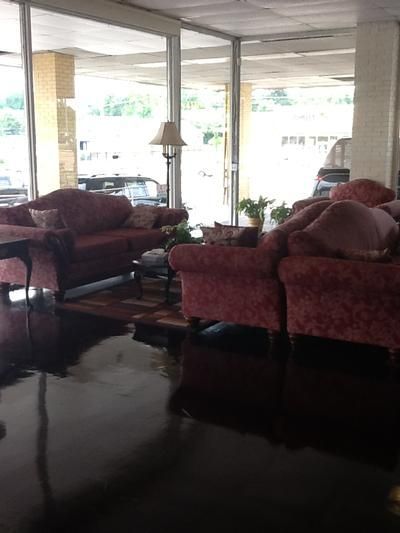 Living room with red sofas, lamps, and glossy dark floor near large windows