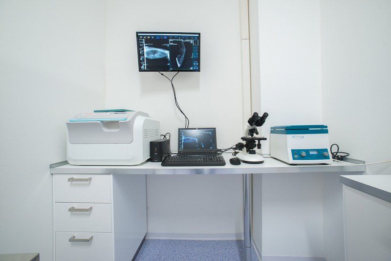 Laboratorio medico con stampante, computer, microscopio e schermo che mostra una radiografia.