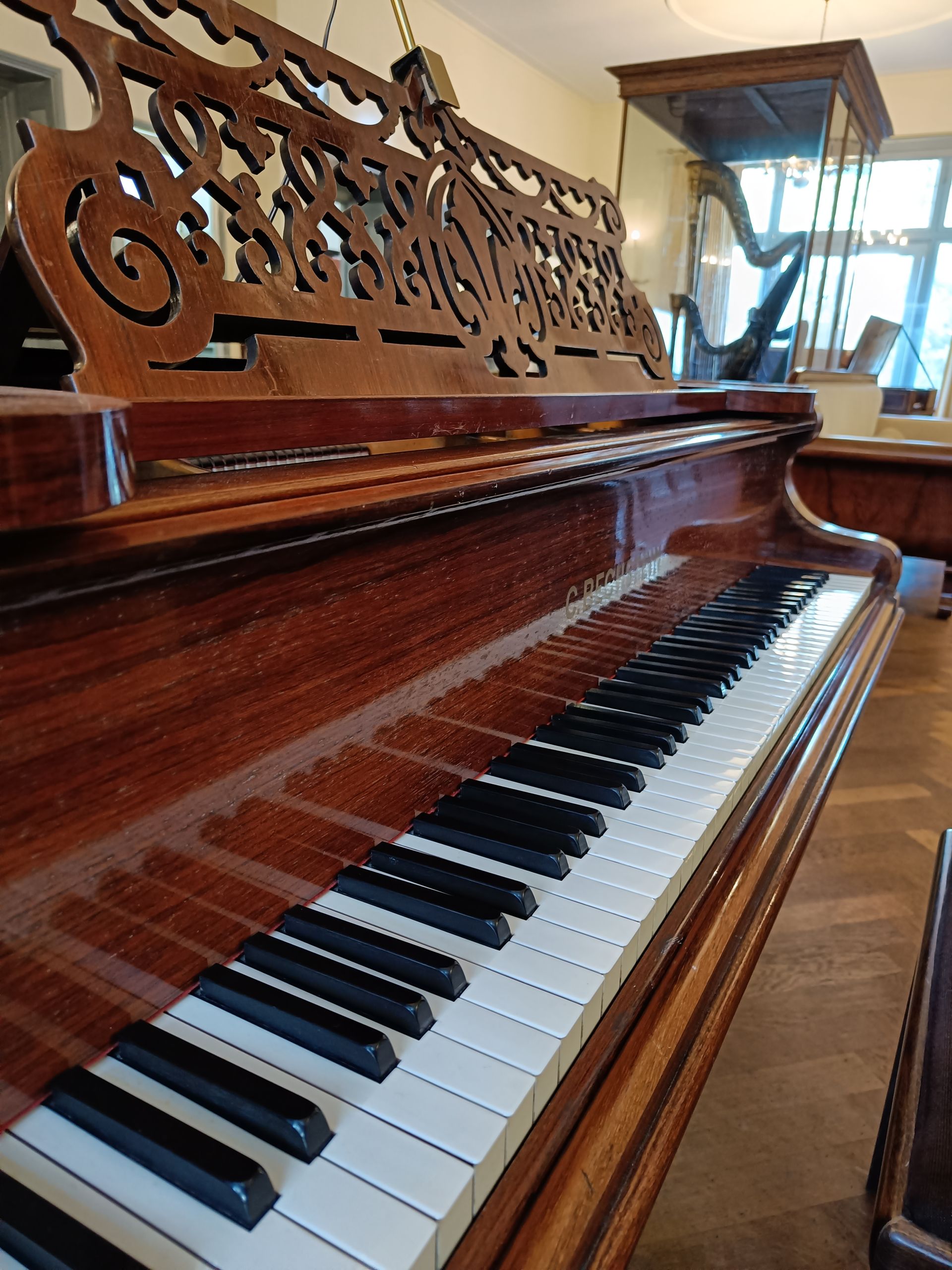 Een piano staat op een houten vloer in een kamer.