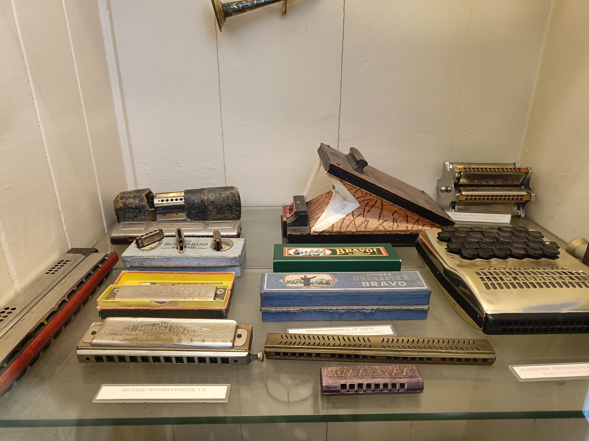 Op een glazen plank staan ​​verschillende mondharmonica-instrumenten tentoongesteld