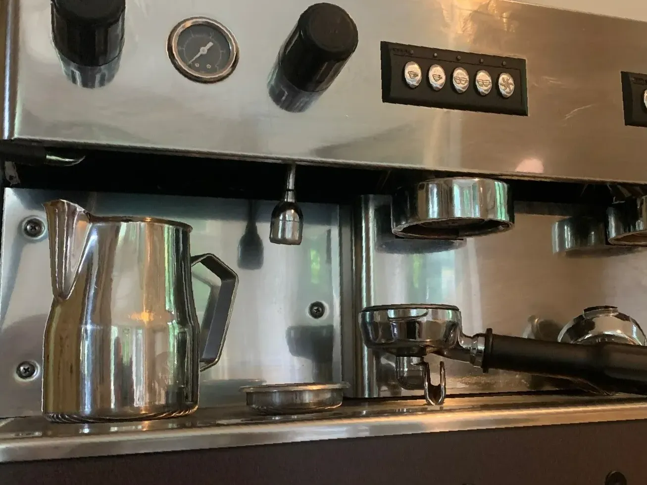 Een roestvrijstalen koffiemachine met een kan ernaast