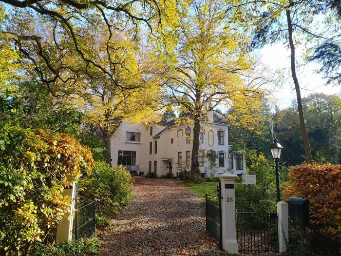 Museum Vosbergen op een zonnige dag omgeven door bomen.