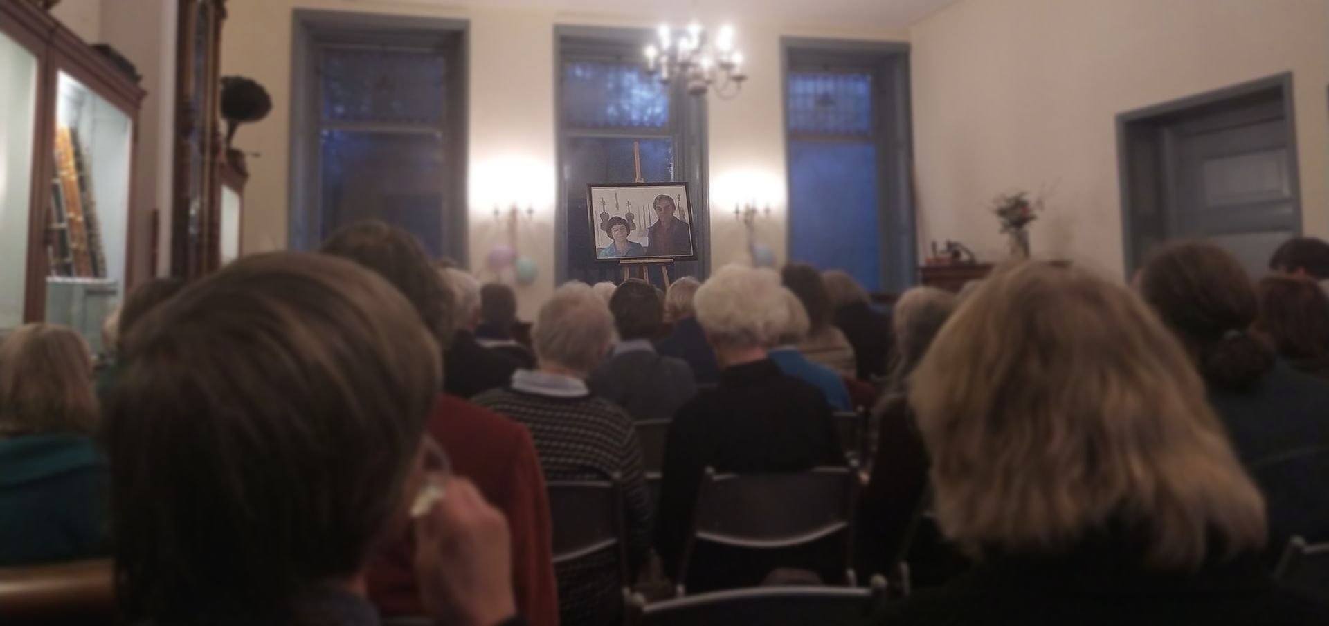 Een groep mensen zit in een kamer en kijkt naar een presentatie.