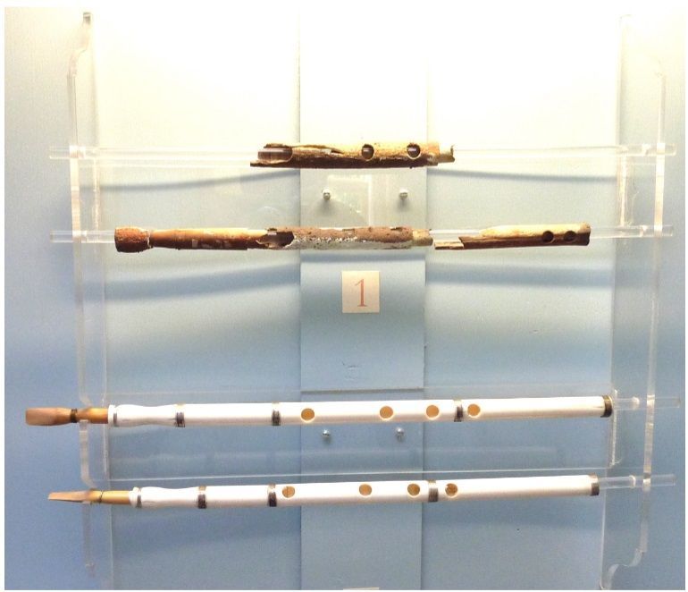 Er staan ​​drie fluiten op een doorzichtige plank met het nummer 1 op de muur erachter