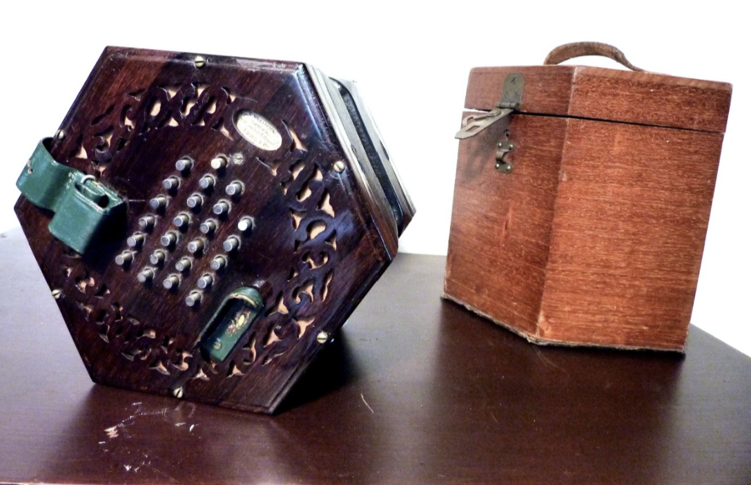 Donkerbruine zeshoekige accordeon met bijbehorende hoes op een donkere ondergrond.