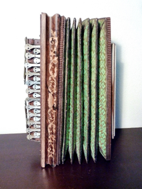 Accordeon, bruin houten frame, groene balg met bloemenpatroon, klavier.
