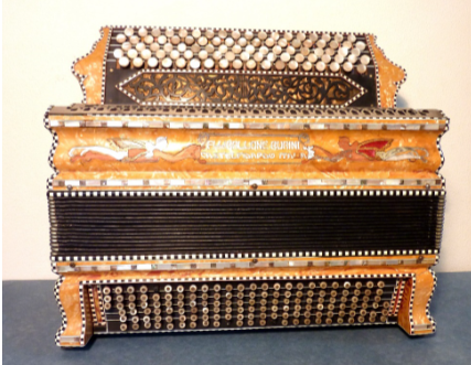 Accordeon met parelmoerversieringen en geschilderde accenten, op een lichtblauwe ondergrond.