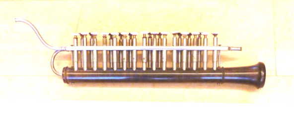 Een oud, lang blaasinstrument met meerdere ventielen en een gebogen metalen buis aan de bovenkant.