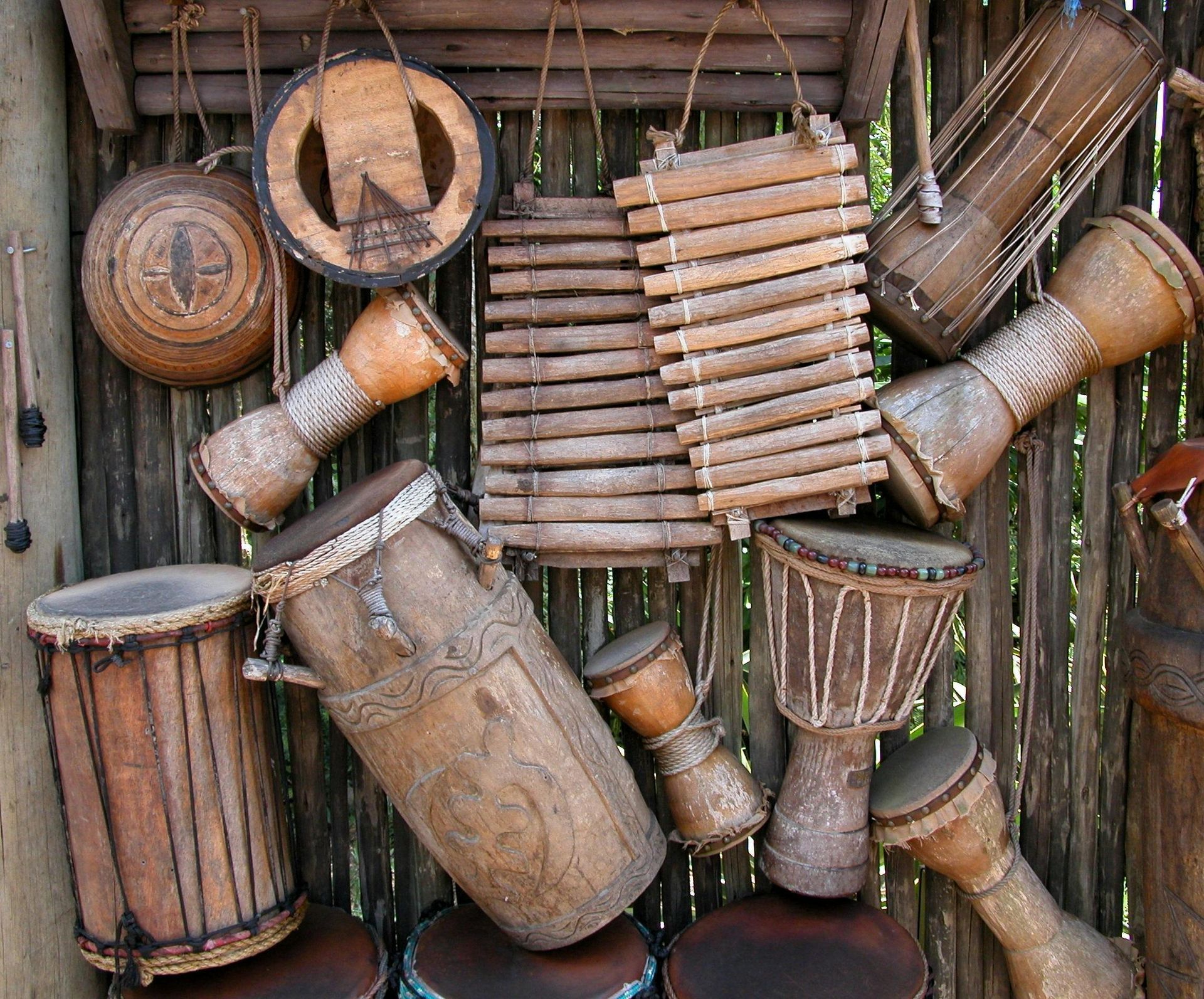 Een verzameling diverse houten Afrikaanse percussie-instrumenten tentoongesteld aan een houten wand.