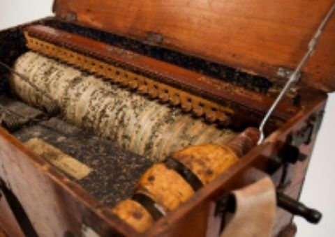 Binnenkant van een houten muziekdoos, met een cilinder met perforaties en mechanische onderdelen.