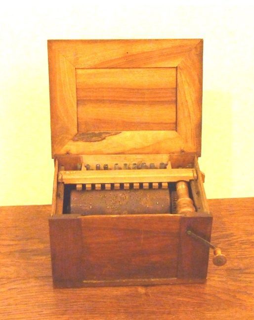 Een kleine houten kist met het deksel open staat op een houten tafel
