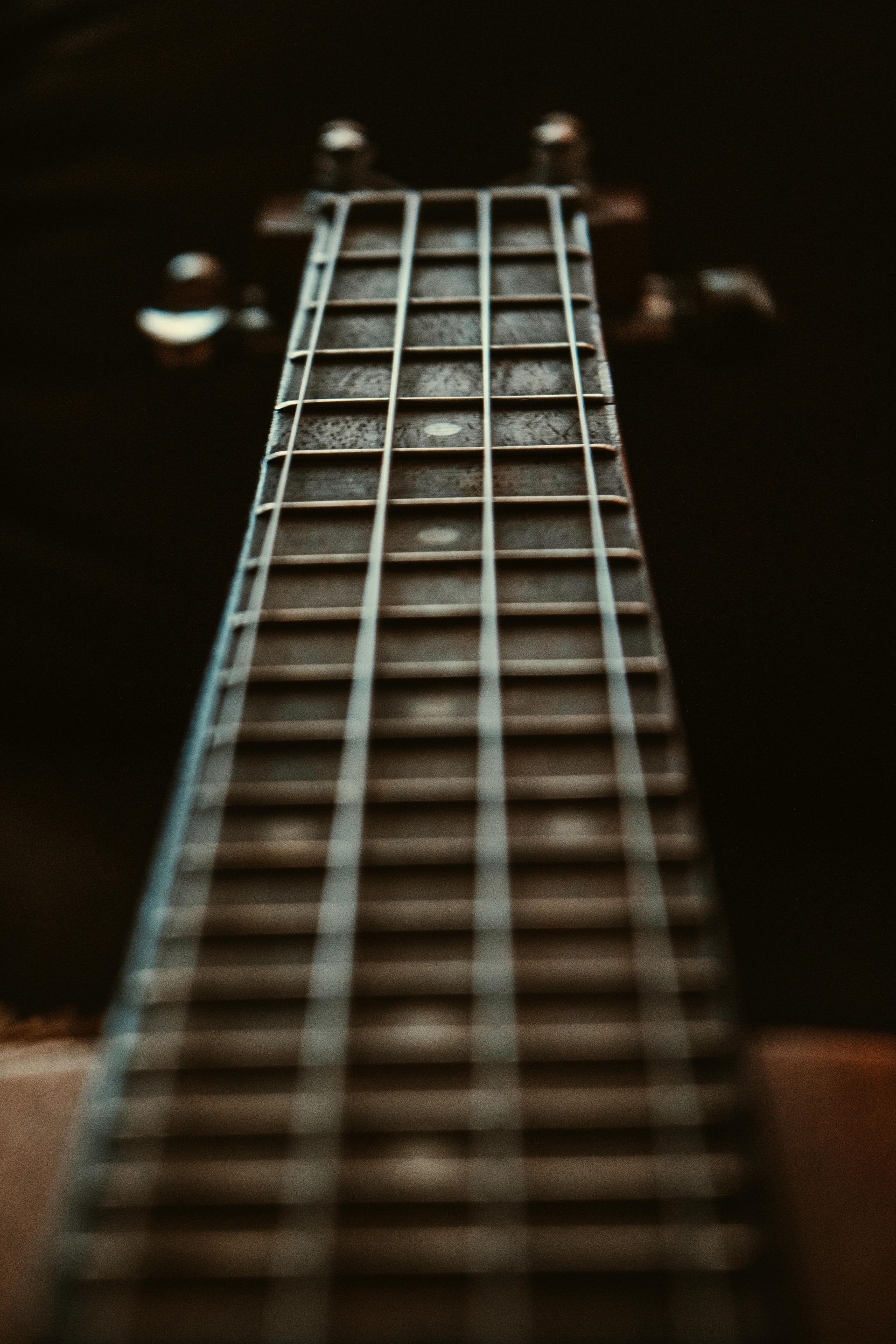 Detailopname van de hals en toets van een ukelele, met een donkere achtergrond.