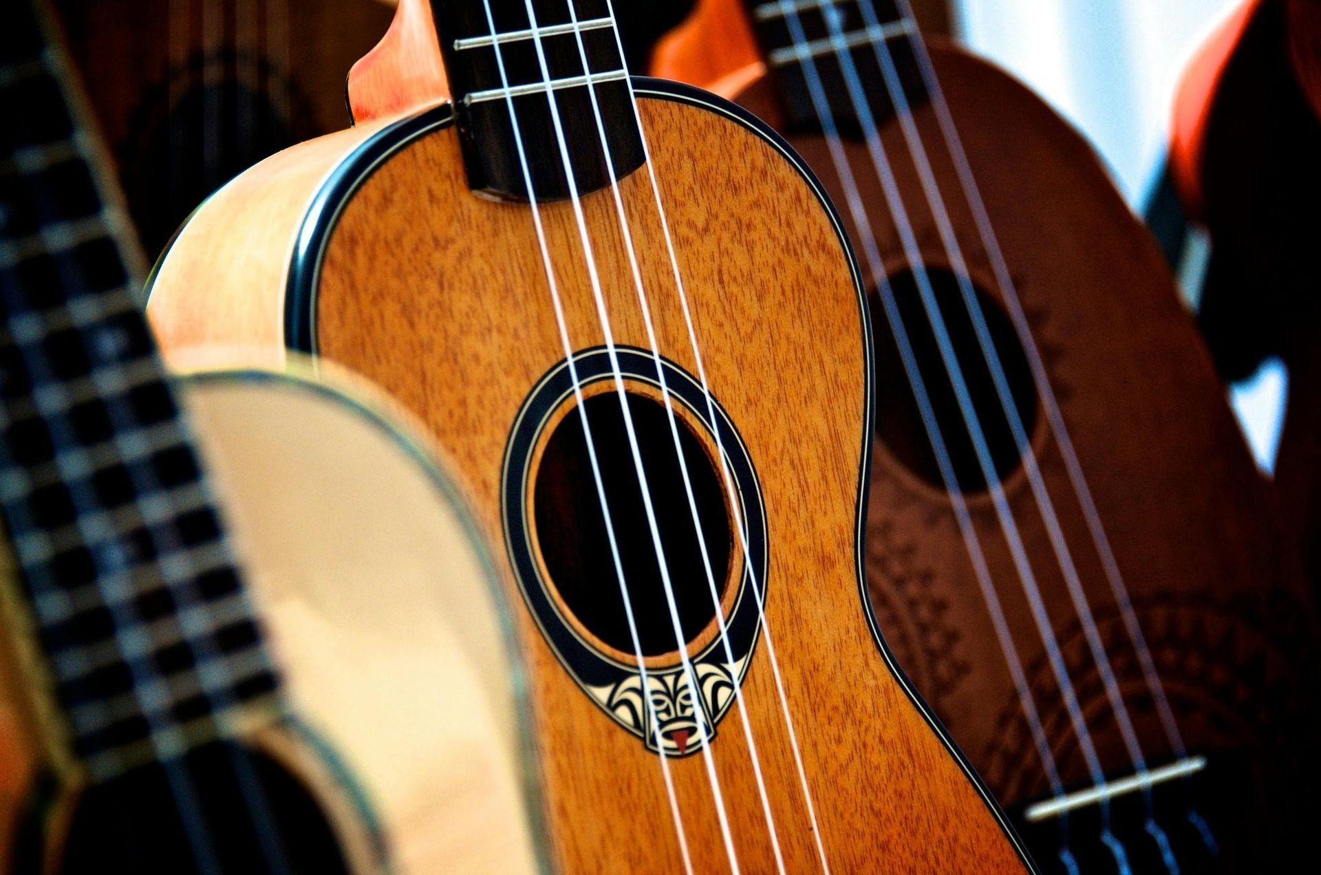 Ukeleles, close-up, houtnerf zichtbaar, snaren, klankgaten, variërende scherptediepte, warme klanken.