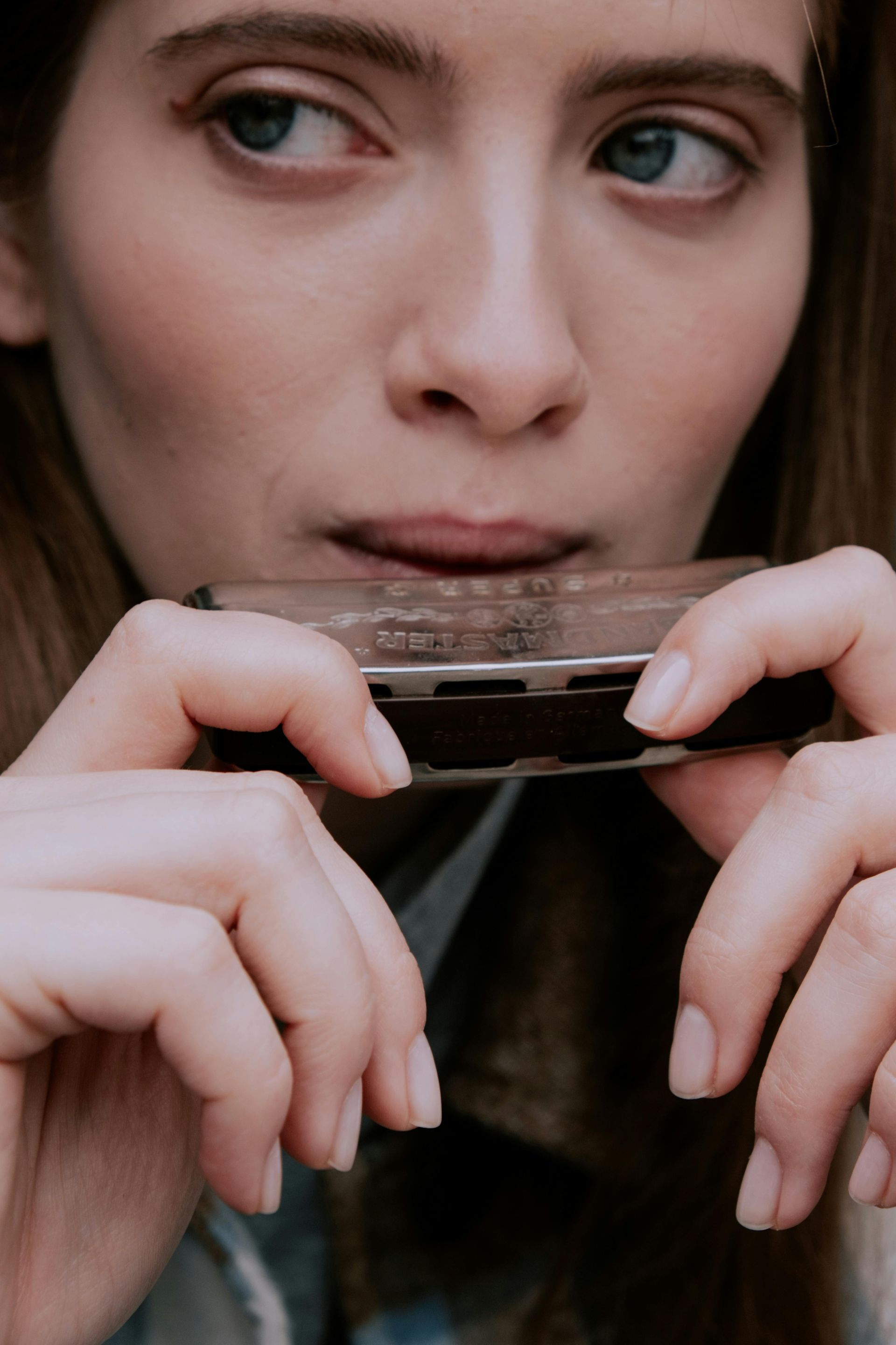 Vrouw die mondharmonica speelt, blauwe ogen, close-up.