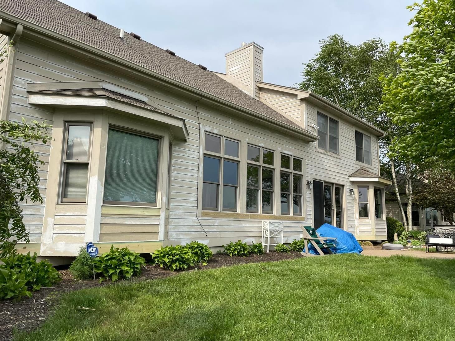 A large white house with a lot of windows is sitting on top of a lush green lawn.