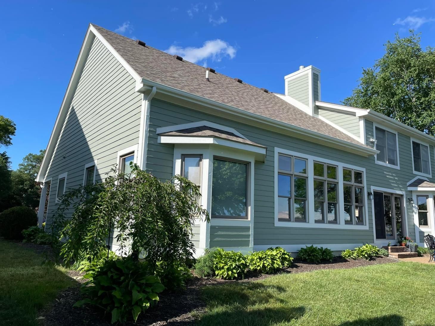 A large house with a lot of windows is sitting on top of a lush green lawn.
