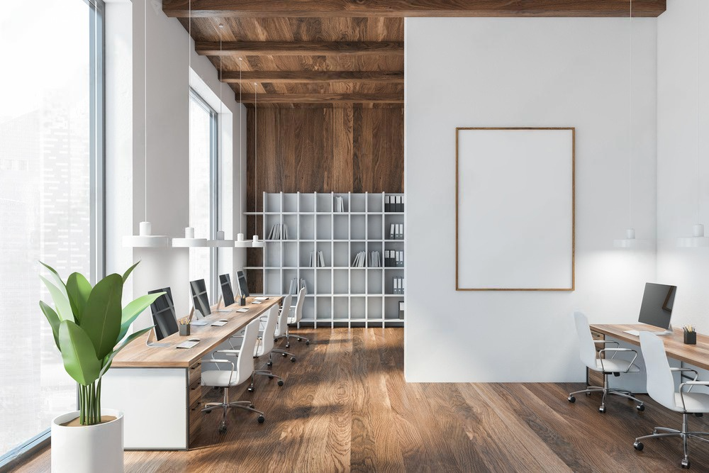 A modern office with wooden floors , white walls and a large window.