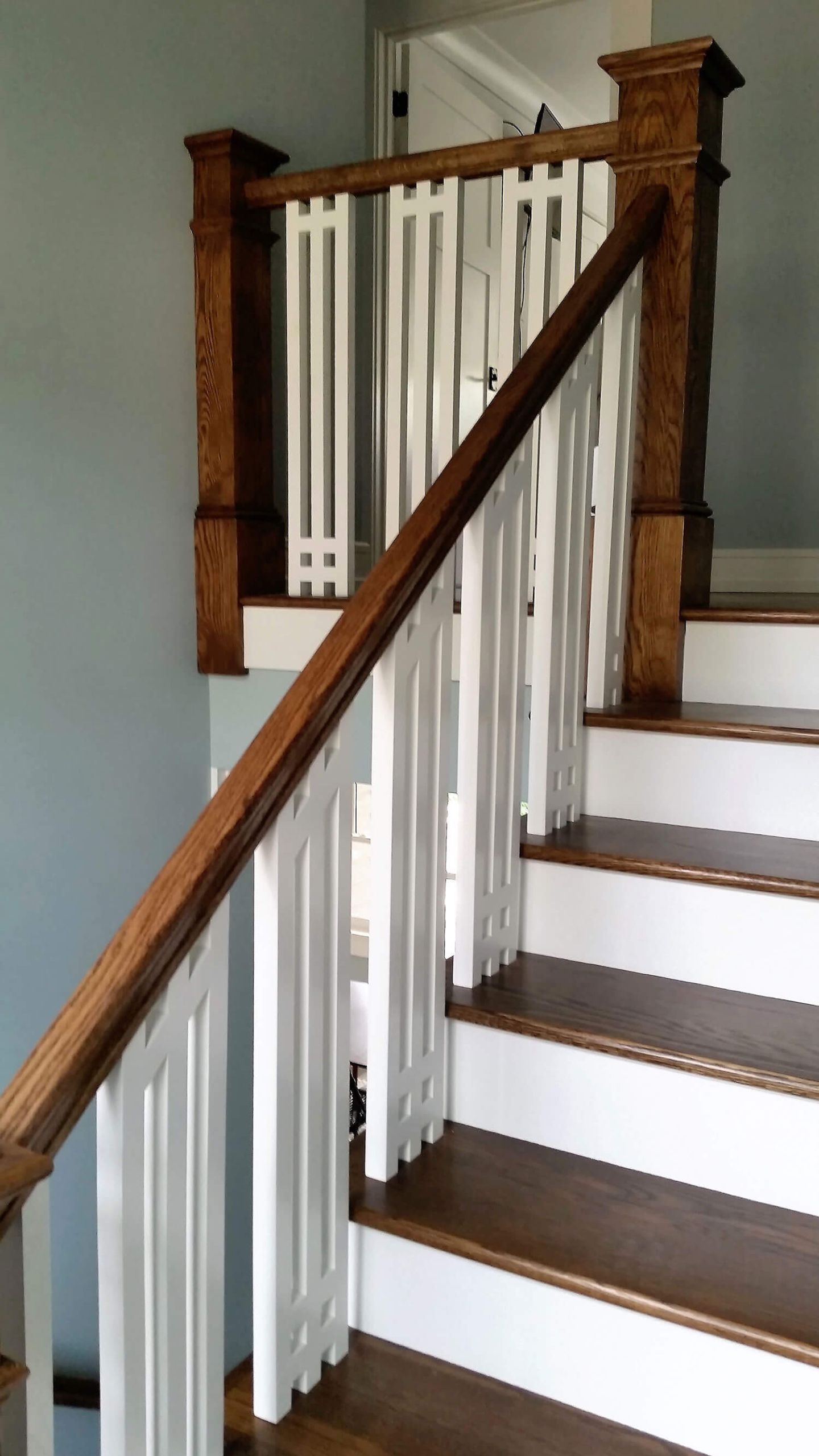 Staircase with white balusters, dark wood railing, and white steps with brown treads