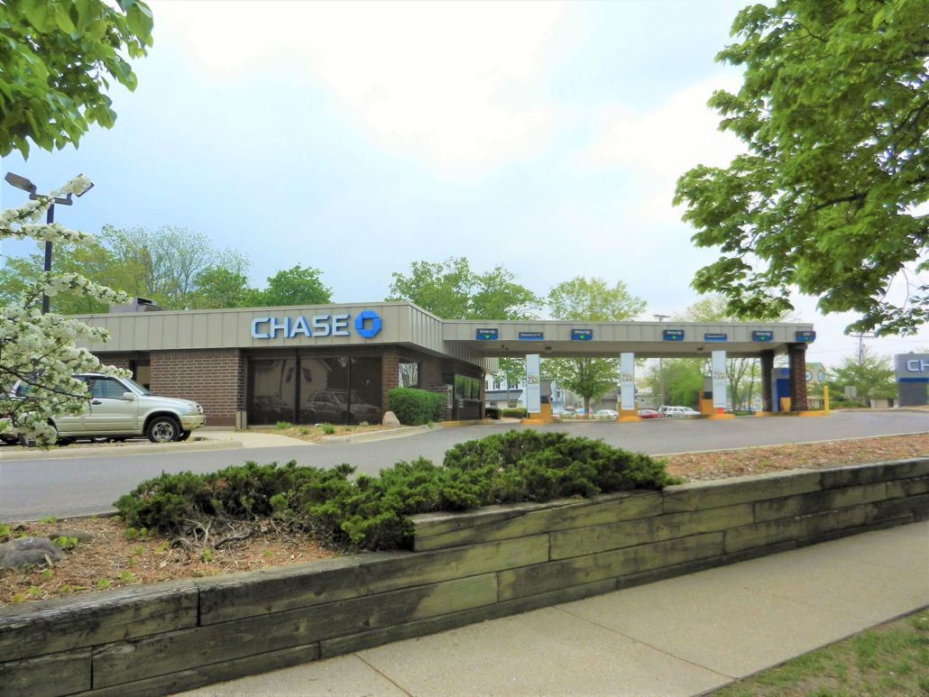 Chase bank branch with drive-thru lanes and parked car under a cloudy sky