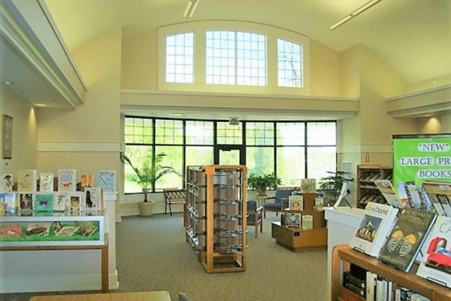 Bright library interior with bookshelves, display racks, and large windows letting in daylight
