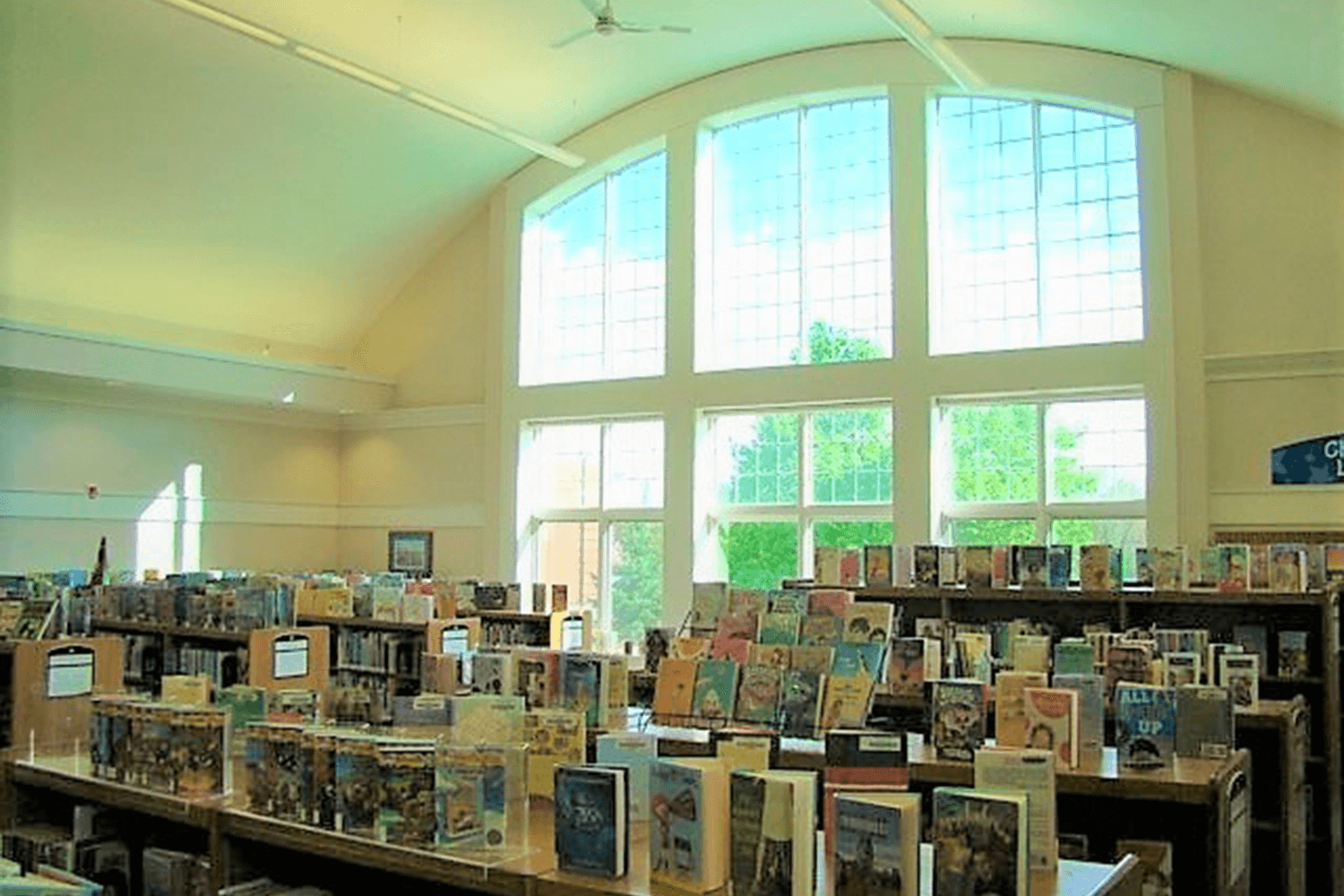 Sunlit library with rows of bookshelves and large arched windows