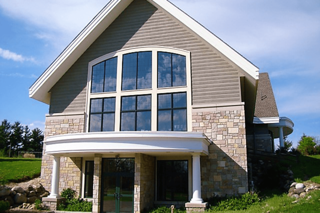 Modern two-story house with stone and beige siding, large windows, and a covered front porch