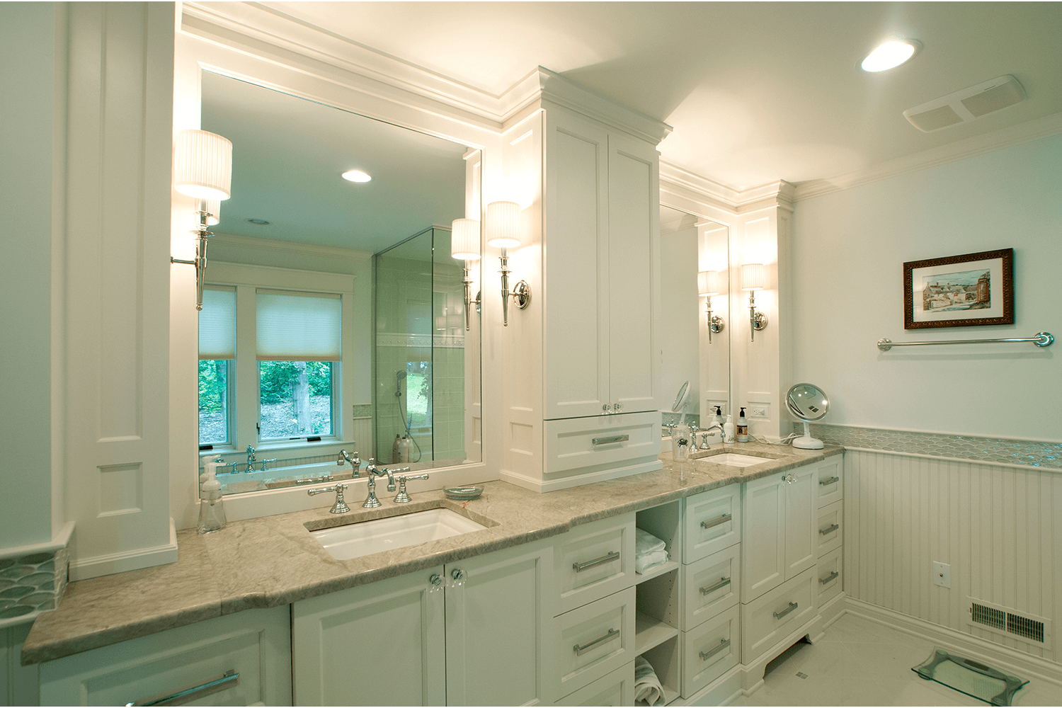 Bright white bathroom with marble vanity, large mirror, sconces, and window light