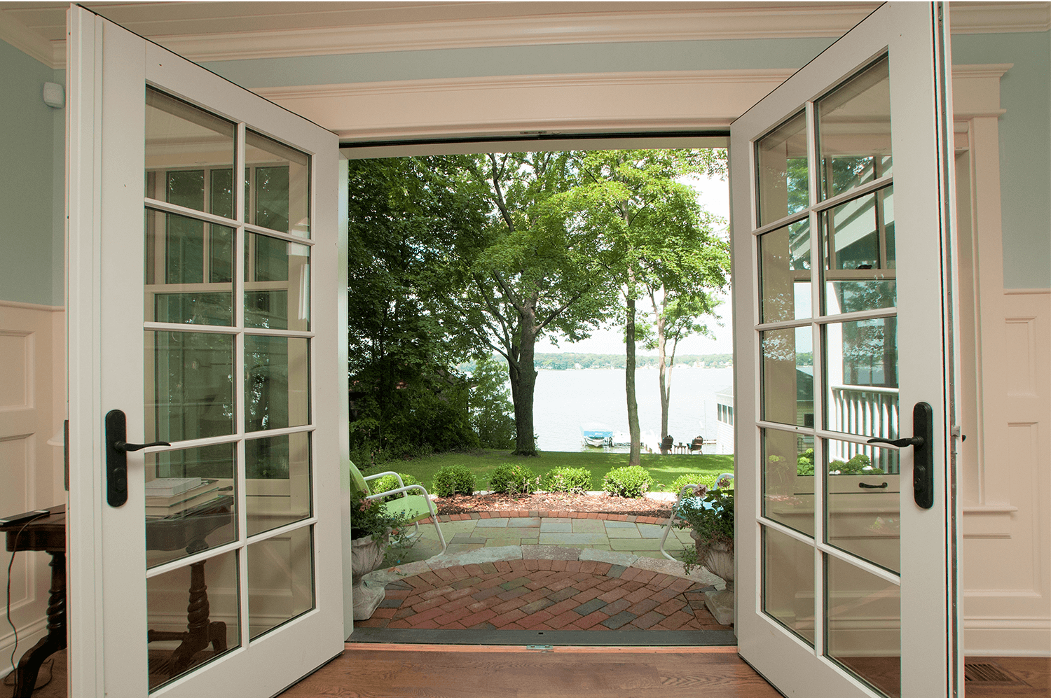 Open French doors framing a lush garden and distant water view