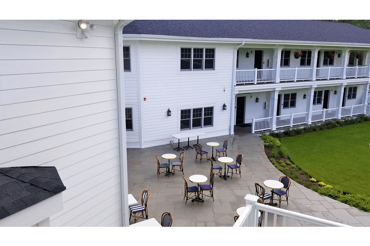 Courtyard patio with tables and chairs outside a white hotel building with balconies