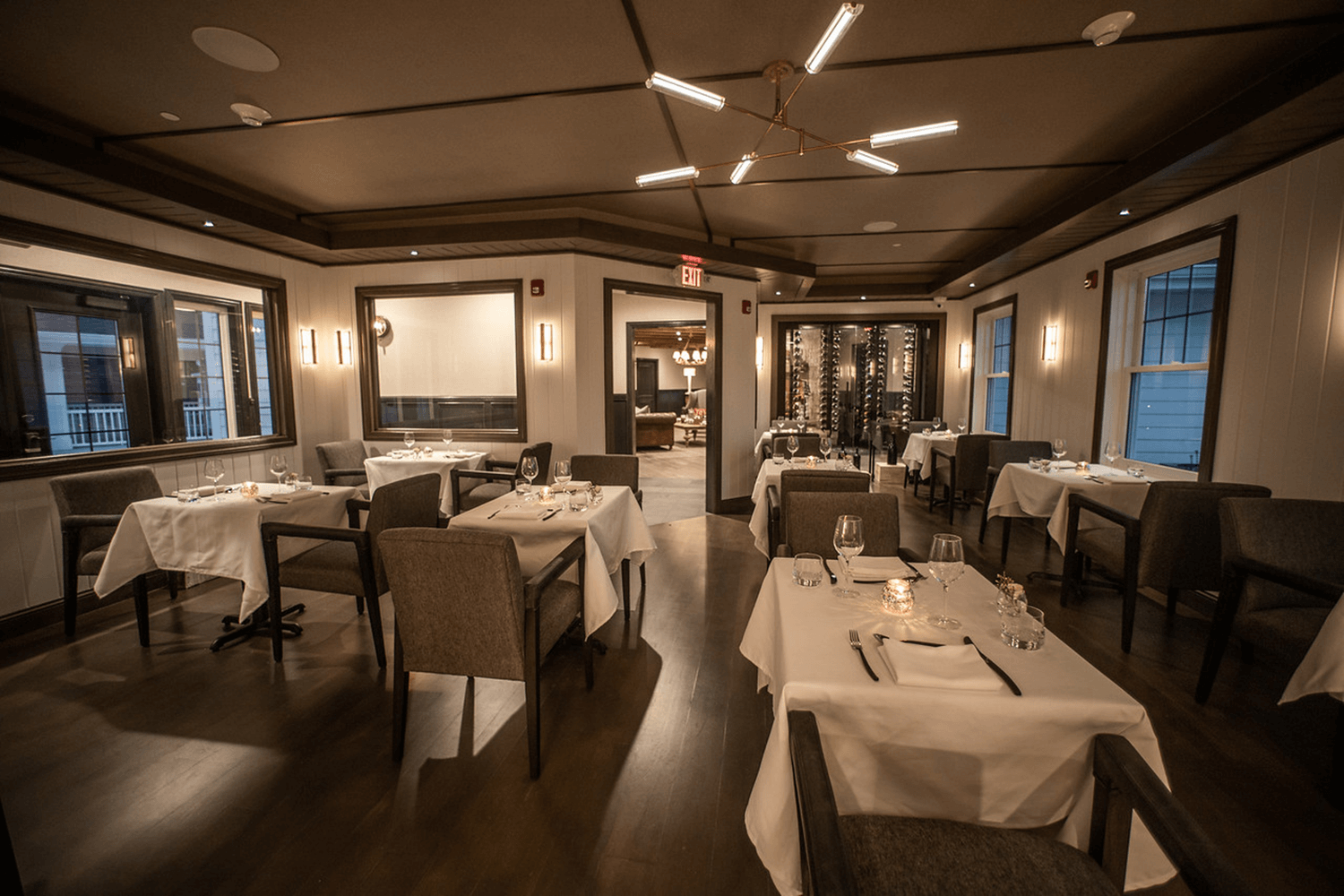 Dimly lit restaurant dining room with white tablecloths and set tables