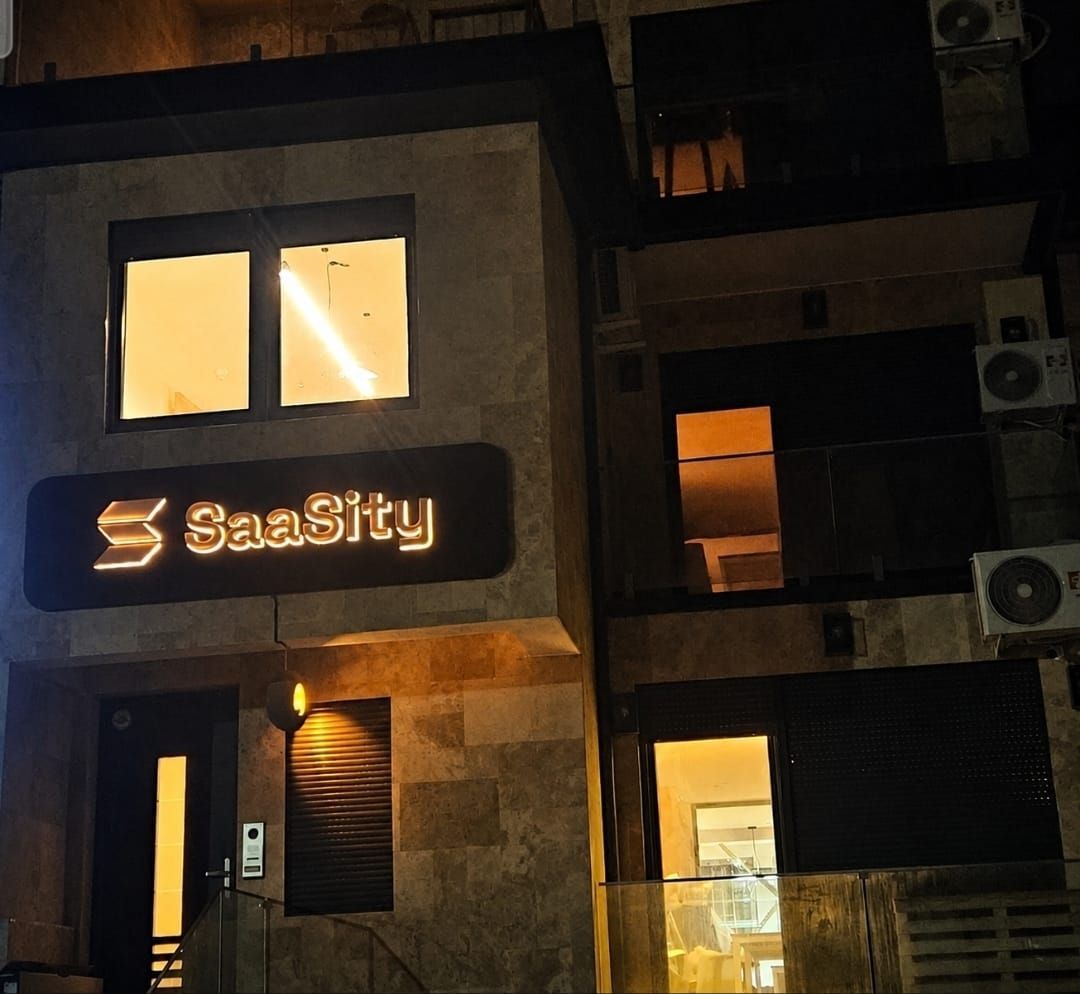 Nighttime exterior of the SaaSity building with lit windows and a company glowing sign.