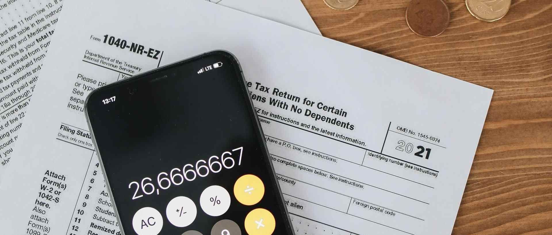 Calculator app open in the phone while laying on tax forms
