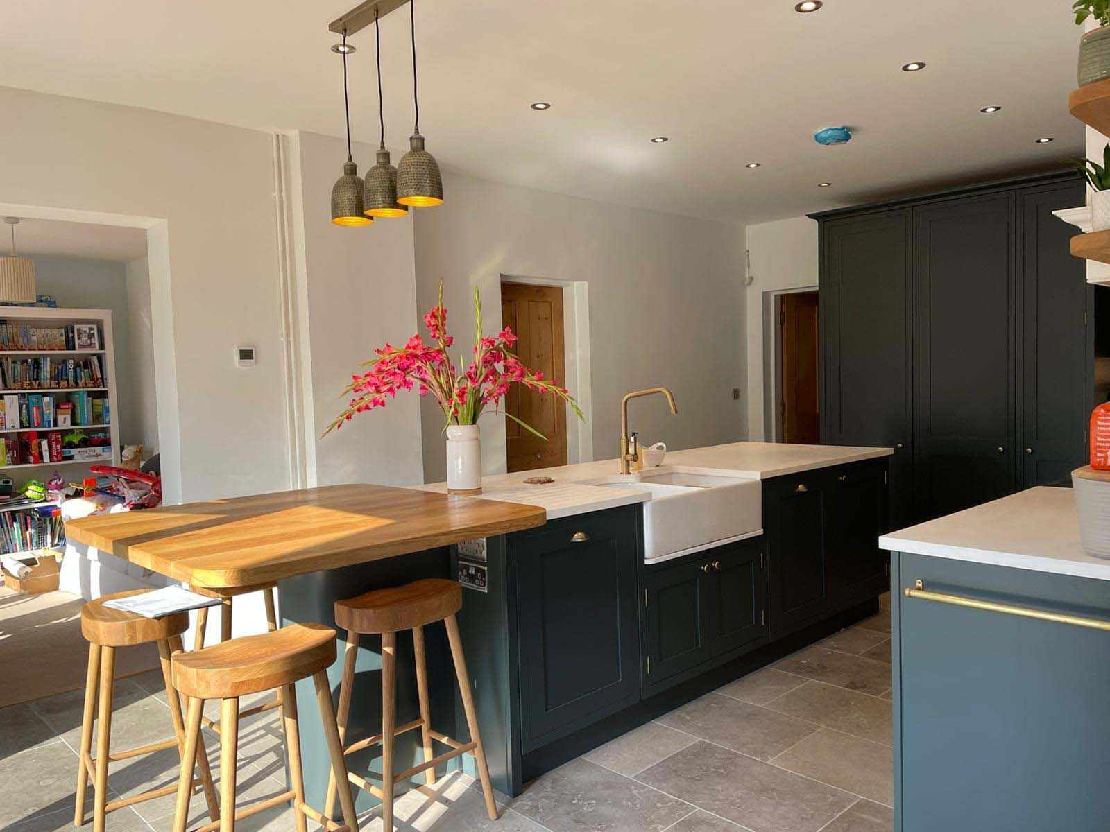 Modern kitchen with black cabinets, white countertops, and a wooden dining table with stools